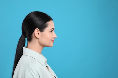 Profile portrait of young woman on light blue background. Space for text