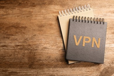 Image of Notebook with acronym VPN and space for text on wooden table, top view. Secure network connection