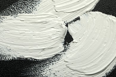 Strokes of white oil paint on black canvas, closeup