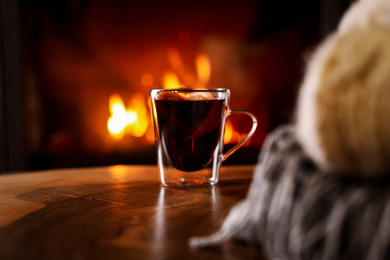 Tasty mulled wine and blurred fireplace on background
