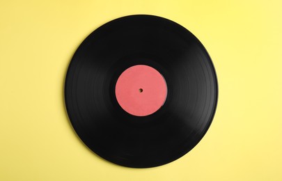 Vintage vinyl record on yellow background, top view