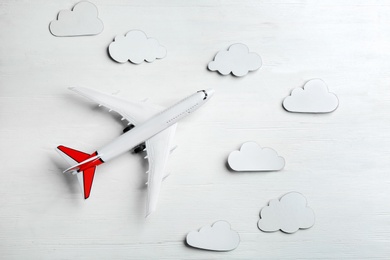 Photo of Toy airplane and clouds on white wooden background, flat lay