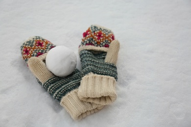 Knitted mittens and snowball on snow outdoors