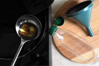 Frying pan of used cooking oil with ladle, empty bottle and funnel in kitchen, flat lay