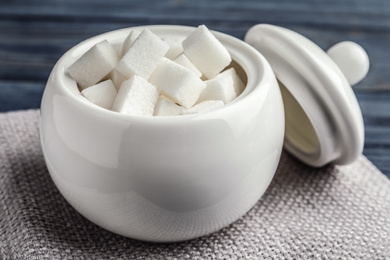 Refined sugar cubes in ceramic bowl on table, closeup