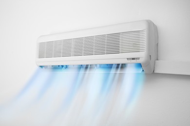 Modern conditioner and illustration of cool air flow on white wall indoors