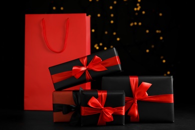 Gift boxes and paper shopping bag against blurred lights. Black Friday sale
