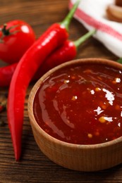 Spicy chili sauce in bowl on wooden table