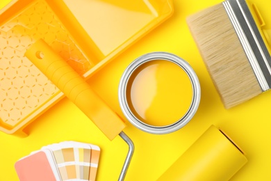 Flat lay composition with can of paint, brush and renovation tools on yellow background