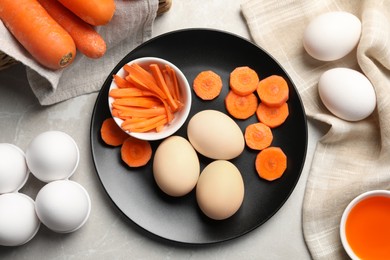 Photo of Naturally painted Easter eggs on light grey table, flat lay. Carrot used for coloring