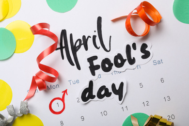 Phrase APRIL FOOL'S DAY and decor on paper calendar, flat lay