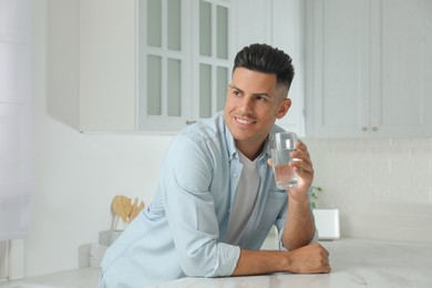 Man with glass of tap water in kitchen
