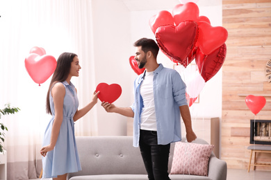 Lovely couple with heart shaped balloons in living room. Valentine's day celebration