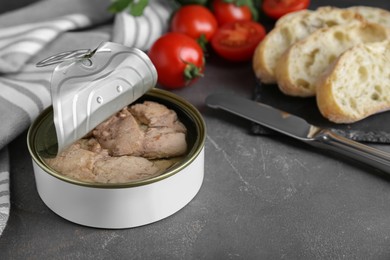 Photo of Open tin can of tasty cod liver on grey table, closeup. Space for text