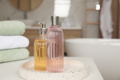 Bottles of shower gels and towels on white table in bathroom, space for text