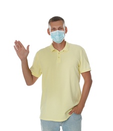 Photo of Man in protective mask showing hello gesture on white background. Keeping social distance during coronavirus pandemic