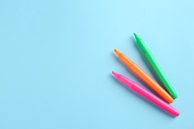 Many colorful markers on light blue background, flat lay with space for text. School stationery