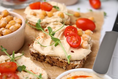 Photo of Delicious sandwiches with hummus and ingredients on wooden board, closeup