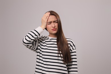 Woman suffering from headache on light grey background. Cold symptoms