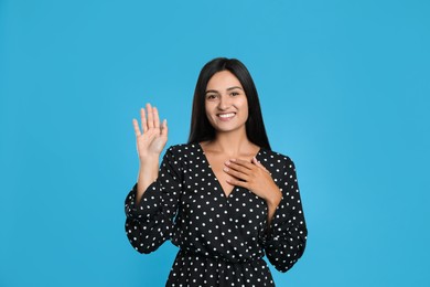 Happy woman waving to say hello on light blue background