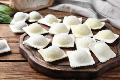Homemade uncooked ravioli on wooden table, closeup
