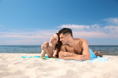 Beautiful woman and her boyfriend sunbathing on beach. Happy couple