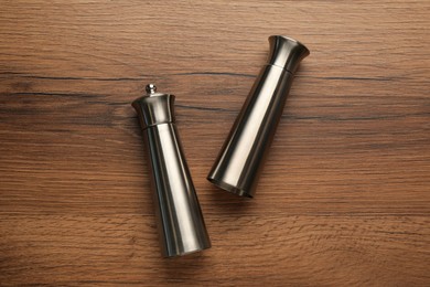 Stainless salt and pepper shakers on wooden table, flat lay