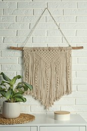 Beautiful macrame hanging on white brick wall in room. Decorative element
