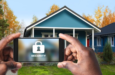 Image of Home security system. African American man with smartphone near his house outdoors, closeup
