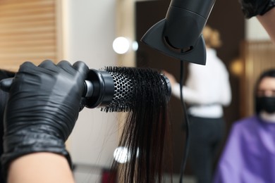 Professional stylist working with client in beauty salon, closeup. Hairdressing services during Coronavirus quarantine