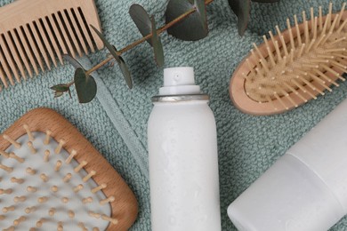 Dry shampoo sprays, hairbrushes and eucalyptus branch on towel, flat lay