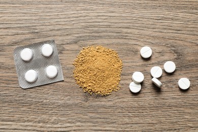 Photo of Pile of sand and pills on wooden table, flat lay. Kidney stone disease
