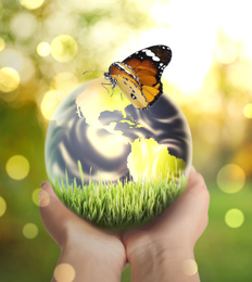 Woman holding Earth with butterfly outdoors, closeup