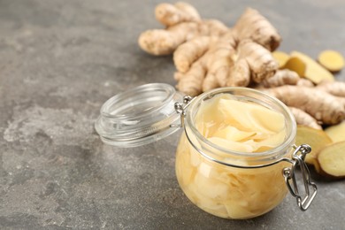 Photo of Spicy pickled ginger and root on light grey table, closeup. Space for text