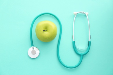 Flat lay composition with stethoscope and apple on color background