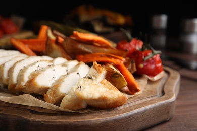 Photo of Tasty cooked chicken fillet and vegetables served on wooden table, closeup. Healthy meals from air fryer