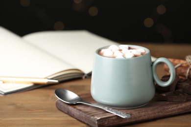 Delicious cocoa drink with marshmallows in cup on wooden table