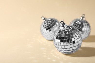 Shiny disco balls on beige background, space for text