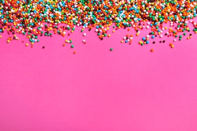 Bright colorful sprinkles on pink background, flat lay with space for text. Confectionery decor