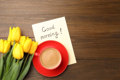 Beautiful yellow tulips, cup of aromatic coffee and Good Morning note on wooden table, flat lay. Space for text