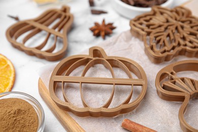 Photo of Cookie cutters of different shapes on white marble table, closeup