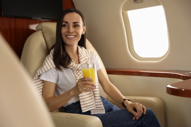 Young woman with glass of juice in airplane during flight