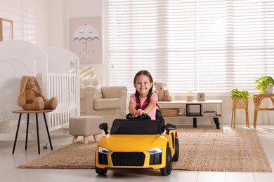 Adorable child driving toy car in room at home