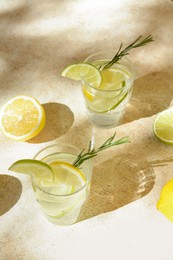 Photo of Glasses of summer refreshing lemonade and ingredients on light table