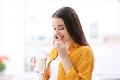 Beautiful pregnant woman drinking milk and eating cookies at home