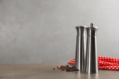 Stainless salt and pepper shakers with napkin on grey table, space for text. Spice mill