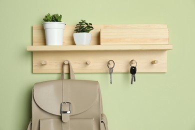 Wooden hanger for keys on light green wall