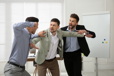 Photo of Man interrupting colleagues fight at work in office