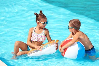 Cute little children with inflatable toys in swimming pool