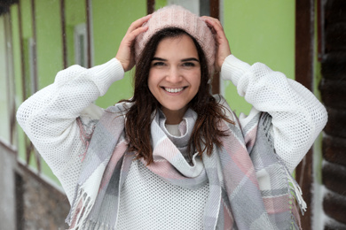 Young woman wearing warm sweater and scarf  outdoors on snowy day. Winter season